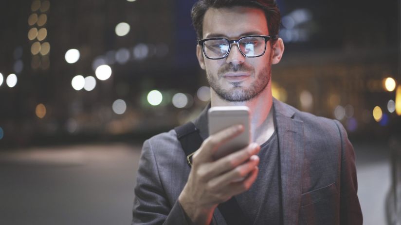 A man looking at his smartphone at night on the street