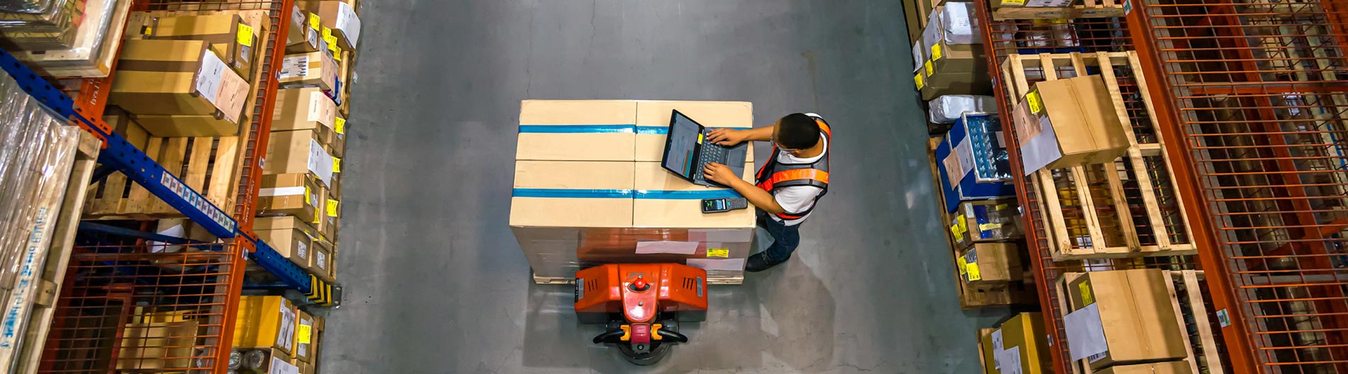 Warehouse employee working on a laptop to track, monitor and manage assets in real time with asset management solutions from Bell.