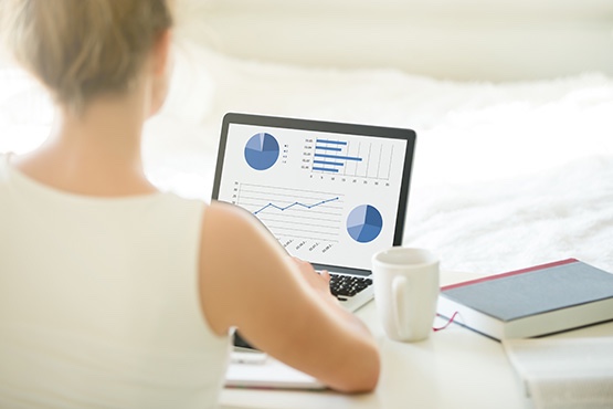 A woman analyzing performance reporting on a laptop