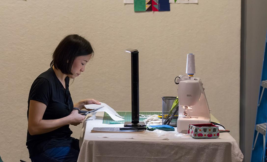 A woman is seen working at a sewing machine.