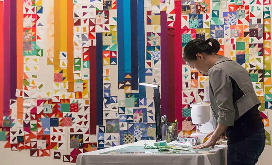 A woman is ironing patches to be added to the quilt.