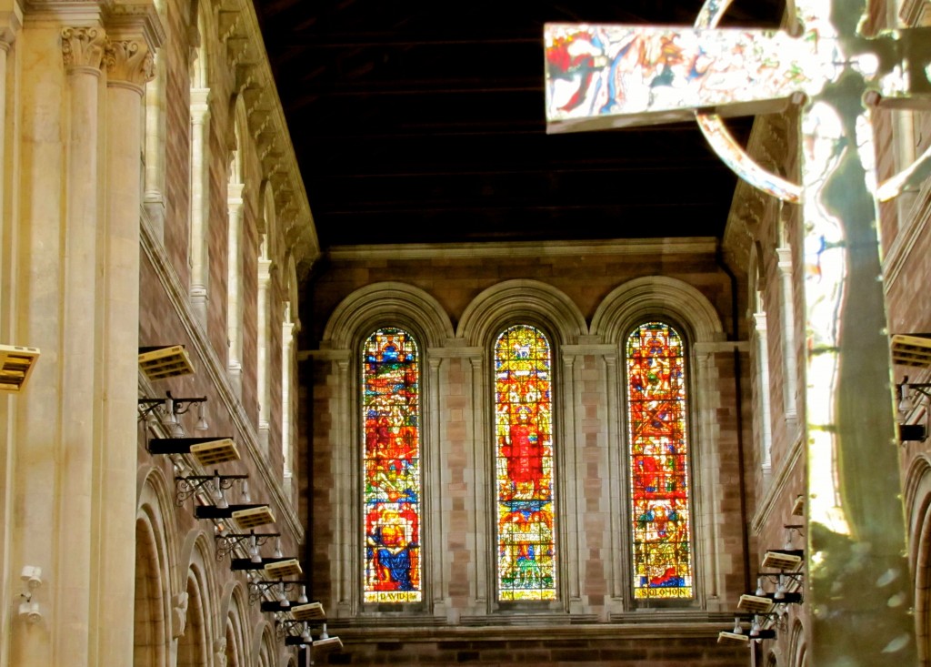 From the Ambulatory, which winds behind the altar and the sanctuary, you can look past a big, silver cross down to the big stained glass windows over the main doors.