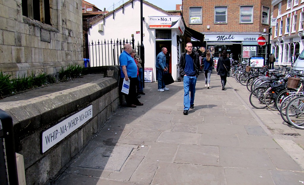 This is Whip-Ma-Whop-Ma Gate, said to be the shortest street in York. It runs from where I'm standing to the Mali salon you see at the end. The numbers on the street are 1, 1B, and 1 1/2. It doesn't reach 2. The name is said to be a corruption of a Danish Viking phrase that means "neither one thing nor another."