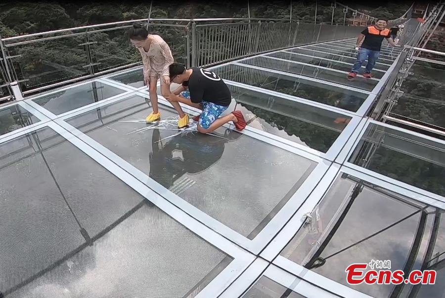 Tourist look at fake cracks on a vertigo-inducing glass bridge suspended over a valley in Qingyuan City, South China’s Guangdong Province, June 28, 2018. The structure also features a massive circular glass observation deck suspended at the end of the bridge, jutting out 72 meters from the cliff edge. (Photo: China News Service/Xu Qingqing)