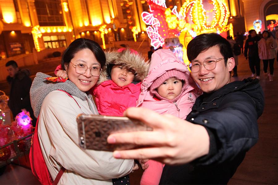 A family of four takes a photo in front of lanterns during the Tourism and Cultural Festival and Lantern Festival in Jinshitan. (Photo by Ma Wenjun/For chinadaily.com.cn)
He considers modern buildings, subway systems, high-speed trains and available goods and services to be the biggest changes during his stay in Dalian.

Row thinks one of the challenges of growing and developing is pollution and keeping things clean, but China is doing a wonderful job on that, he added, and everybody has benefited from continue efforts to protect the environment.