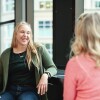 Two woman engage in a conversation with each other in an Amazon office. 