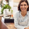 A woman working in a small business leans toward the camera.