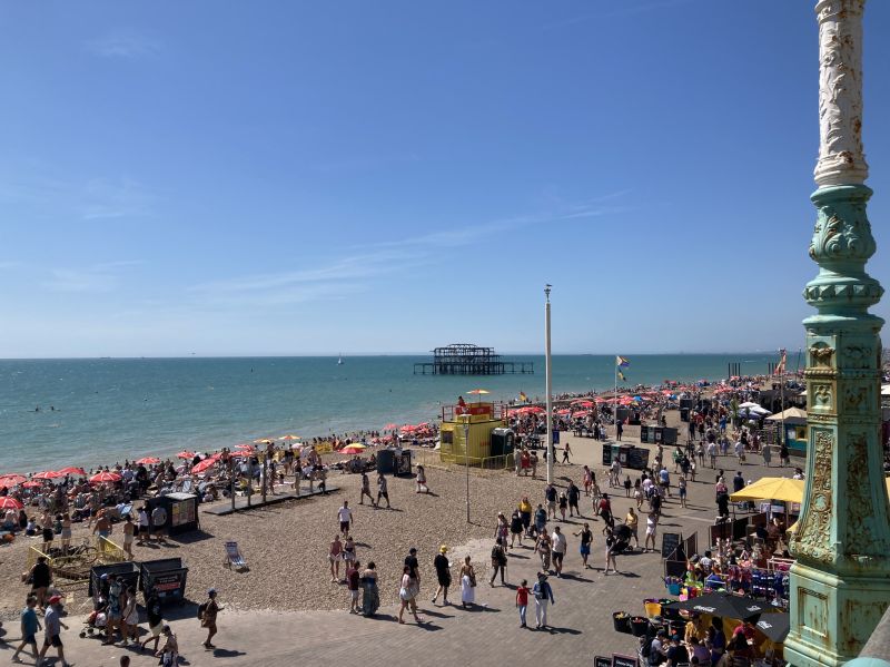 A bustling seafront with the green sea under a clear blue sky.