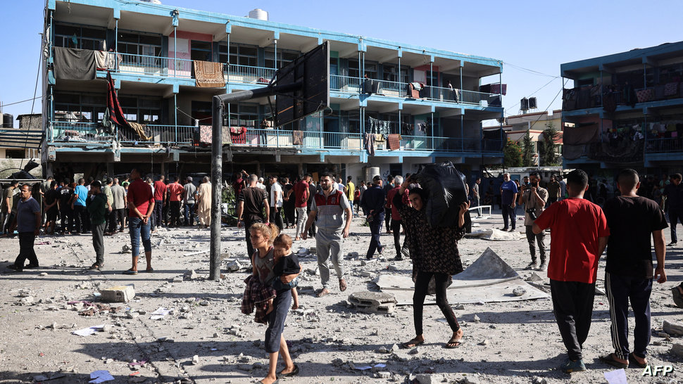 Palestinians walk in the courtyard of the Al-Jawni (Jaouni) school after an Israeli air strike hit the site, in Nuseirat in the…