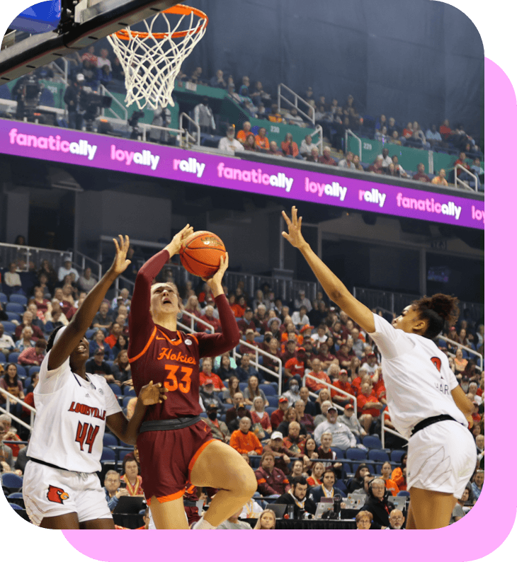 A basketball player leaping in the air, attempting to make a layup shot in-between two defenders.