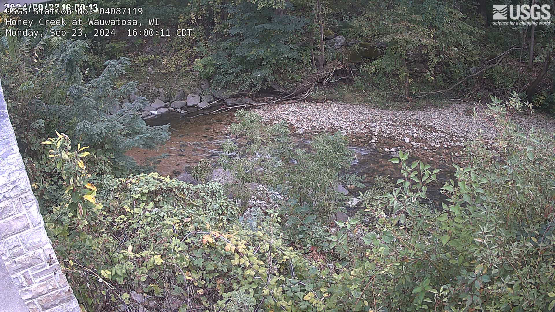 Overlooking a creek with rock and brush on both sides.