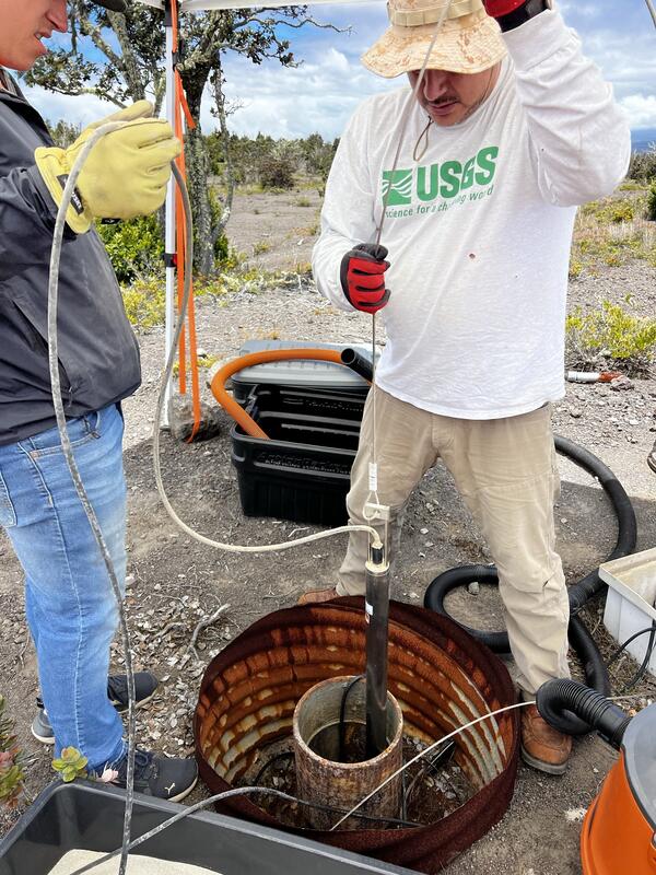 Color photograph of field engineer adjusting volcano-monitoring instrument