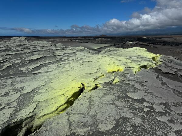 Color photograph of ground cracks and sulfur deposits