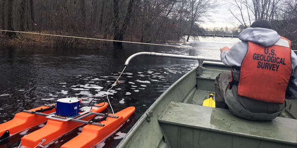 A manned boat is pulled back and forth across the river on a static line to make smooth transects for an ADCP measurement. 