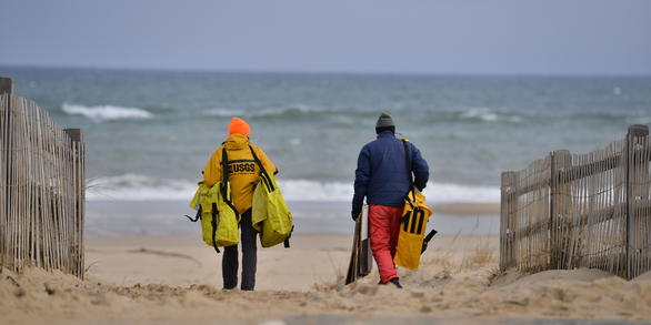 Photograph of USGS staff carrying equipment walking to the beach