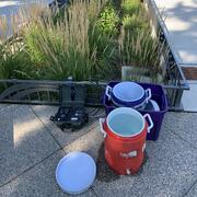 Two cylindrical coolers and water quality monitoring equipment next to greenery planted in a sidewalk urban environment.