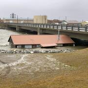 A building lifted from its foundation by floodwater from Typhoon Merbok is trapped under a bridge in Nome, Alaska