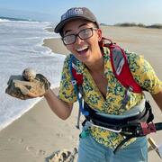 Scientist standing on the beach holding a fish