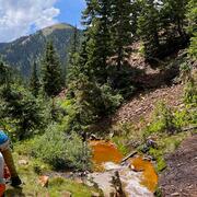 scientists sampling next to mine-drainage impacted stream in mountains