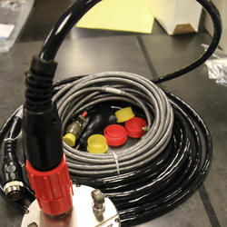 close-up of steel cylinder with cables and bright red and yellow caps coming out of it.