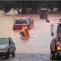 Picture of tow truck driver assisting car stuck in flood waters.