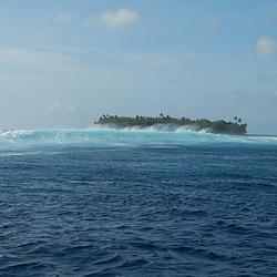 Waves brush past a low-lying island off the shore of Kwajalein Island.