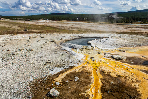 Yellowish bacteria in water flows out of a blue colored hot spring in the shape of an ear.