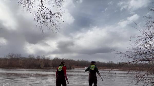 USGS scientists walk into the Rio Grande to collect water samples for a PFAS study near Valle de Oro, New Mexico.