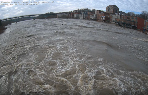 A river flooding with a city in the background.