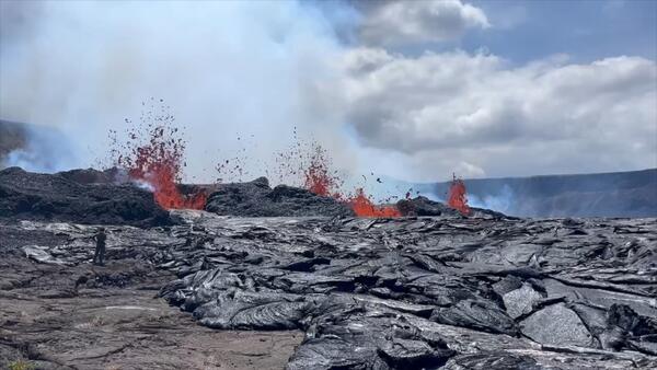 Lava erupting from the caldera as a person stands nearby