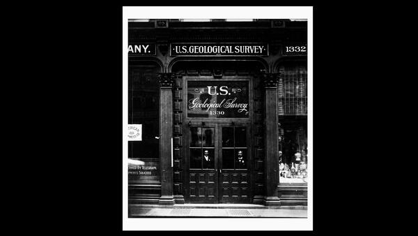 Historical photo of the entrance to a library with tall doors and the words U.S. Geological Survey on the window above the door.