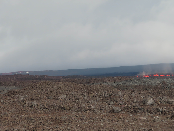 A helicopter flies over the lava flow