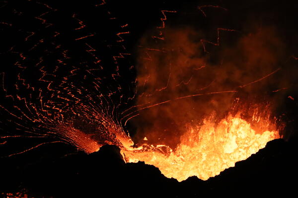 Nighttime color photograph of lava fountains erupting within a spatter cone