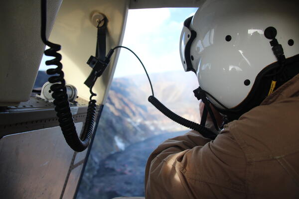 Color photo of a scientist taking photos from a helicopter