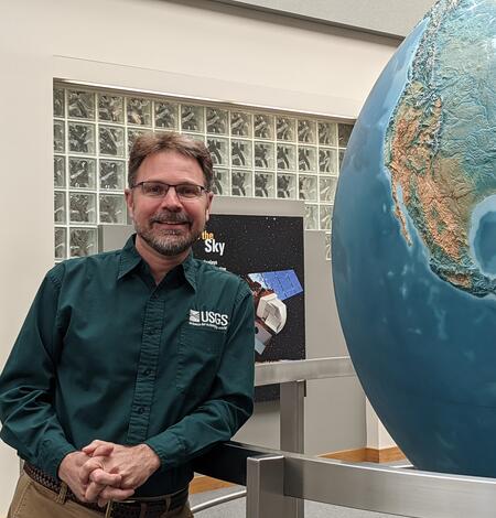 A man stands next to a very large globe