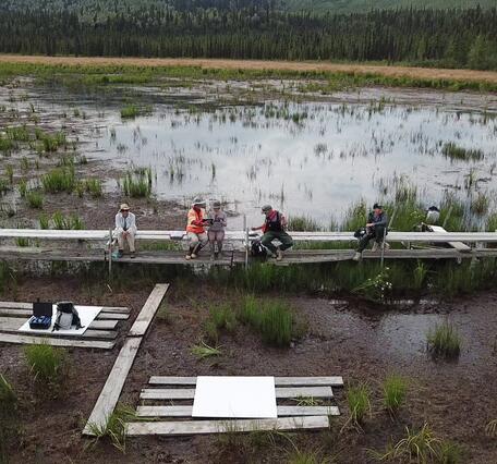 Field crew sit on boardwalk while collecting UAS methane measurements in Alaska 2023