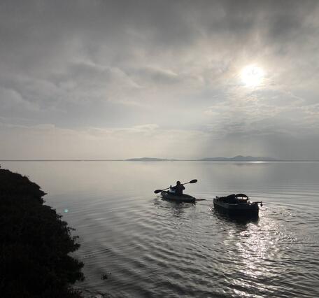 A USGS researcher in a kayak tows instruments to measure water level and suspended-sediment concentration