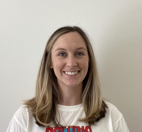 Head shot of a female with shoulder length brown hair and brown eyes wearing a white sweater.