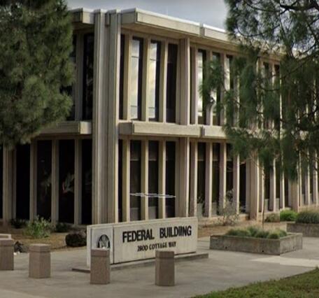 Corner view of federal building on Cottage Way framed by trees