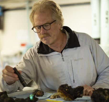 A man shines a small light on some rock samples.