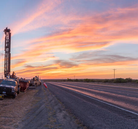 An image of USGS research drilling rig on side of U.S. Route 90 in Kinney County, Texas.  The sky is streaked with clouds. 