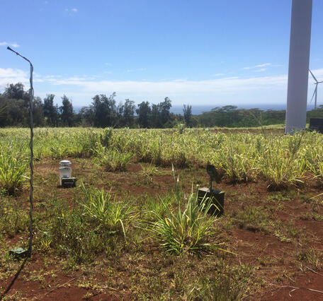 Equipment set up on the ground below a wind turbine.