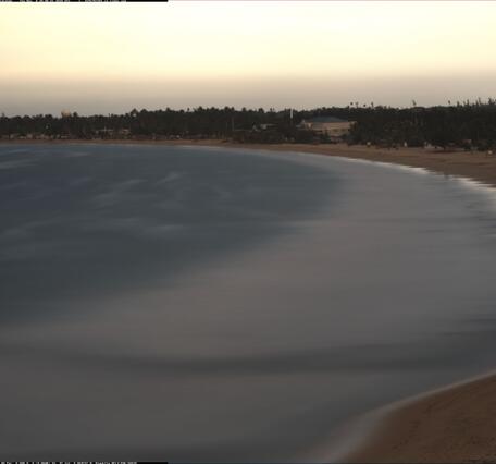 Time exposure image shows a curving beach and the water is smooth where waves were breaking over a 10-minute period.