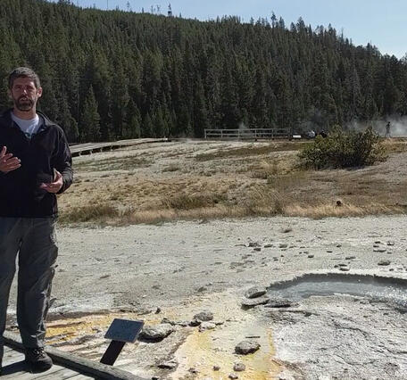 Man standing next to a geyser