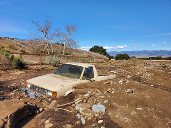 tan pickup truck surrounded by mud and rocks up to the top of the door