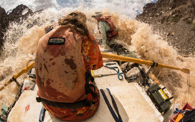 A river guide rows her raft through a big rapid in Grand Canyon