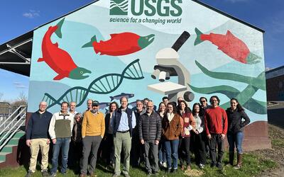 Director and Western Fisheries Research Center staff in front of mural 