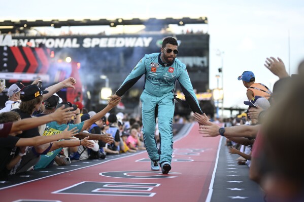 FILE - Bubba Wallace interacts with spectators while walking down a runway during driver introductions before a NASCAR Cup Series auto race at Daytona International Speedway, Aug. 24, 2024, in Daytona Beach, Fla. (AP Photo/Phelan M. Ebenhack, File)