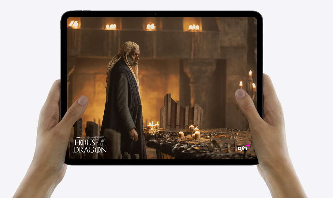 A pair of hands holding an iPad Pro showcasing the TV app while it plays the show "Monarch: Legacy of Monsters."