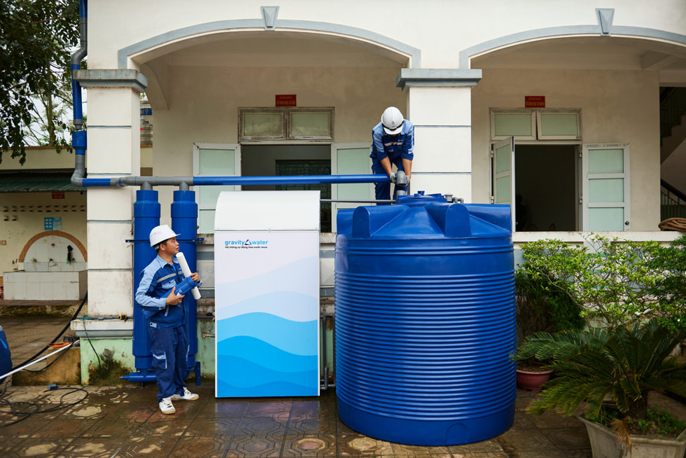 Iemand inspecteert het systeem van Gravity Water, terwijl iemand anders toekijkt.